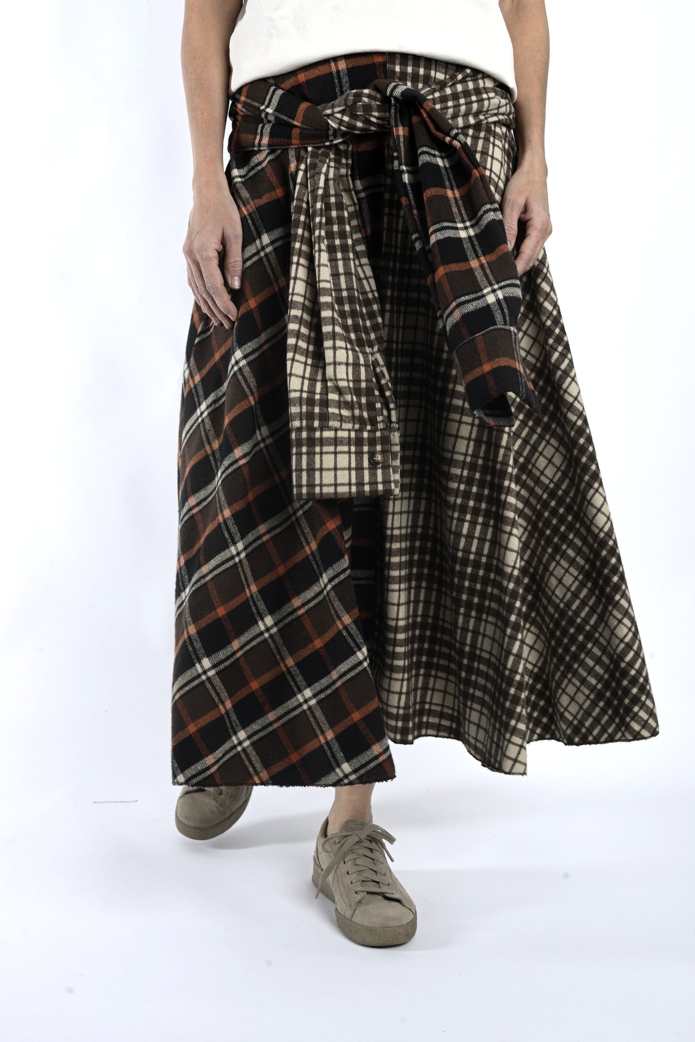 Detaliu de talie cu legare și suprapunere, evidențiind carourile contrastante ale fustei midi.