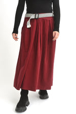 Fustă midi roșie din catifea reiată, cu talie elastică și design lejer, purtată de model.