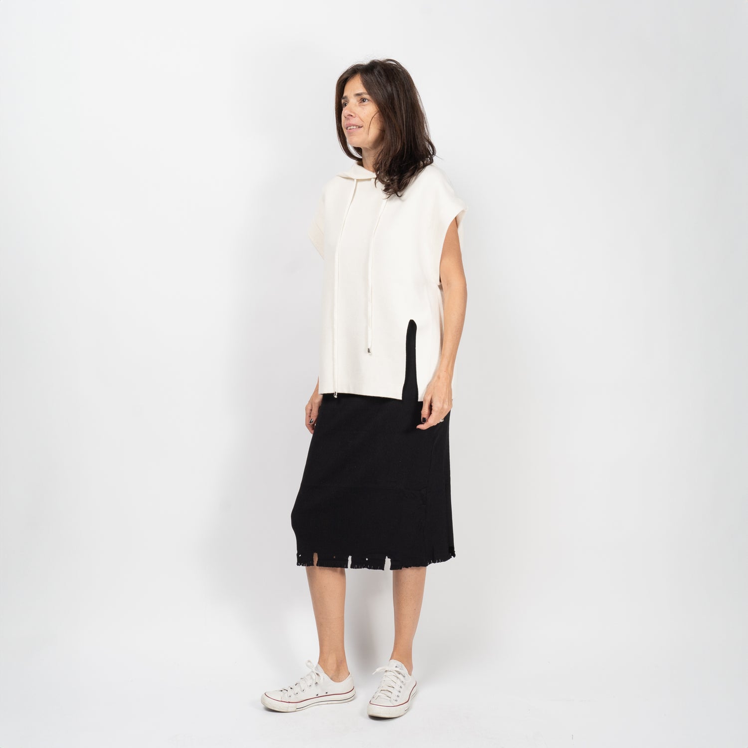 Outfit casual cu fustă midi din rib neagră, purtată cu sneakers albi și pulover crem.