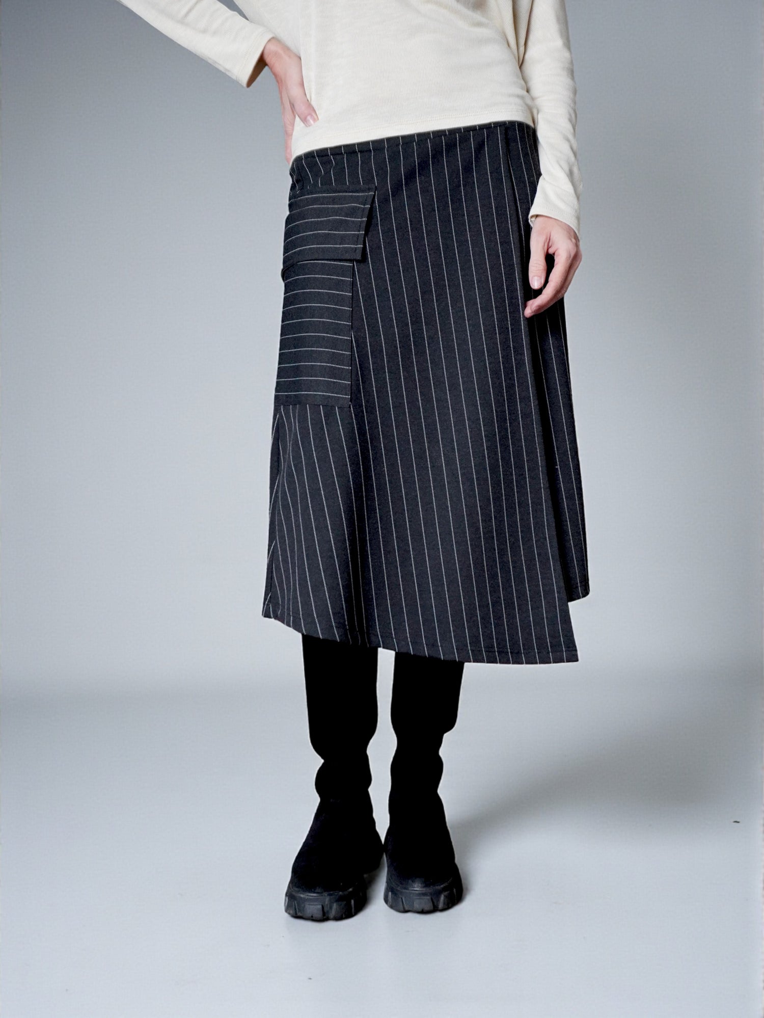Detaliu buzunar aplicat cu clapă pe fustă midi gri în dungi, cu finisaj atent.