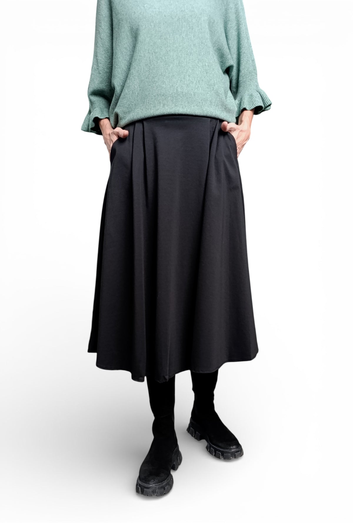 Fustă midi evazată neagră, purtată cu pulover verde, cu talie elastică și siluetă lejeră, potrivită pentru layering.