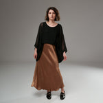Fustă satinată cognac purtată cu bluză neagră vaporoasă, pentru un look elegant și relaxat