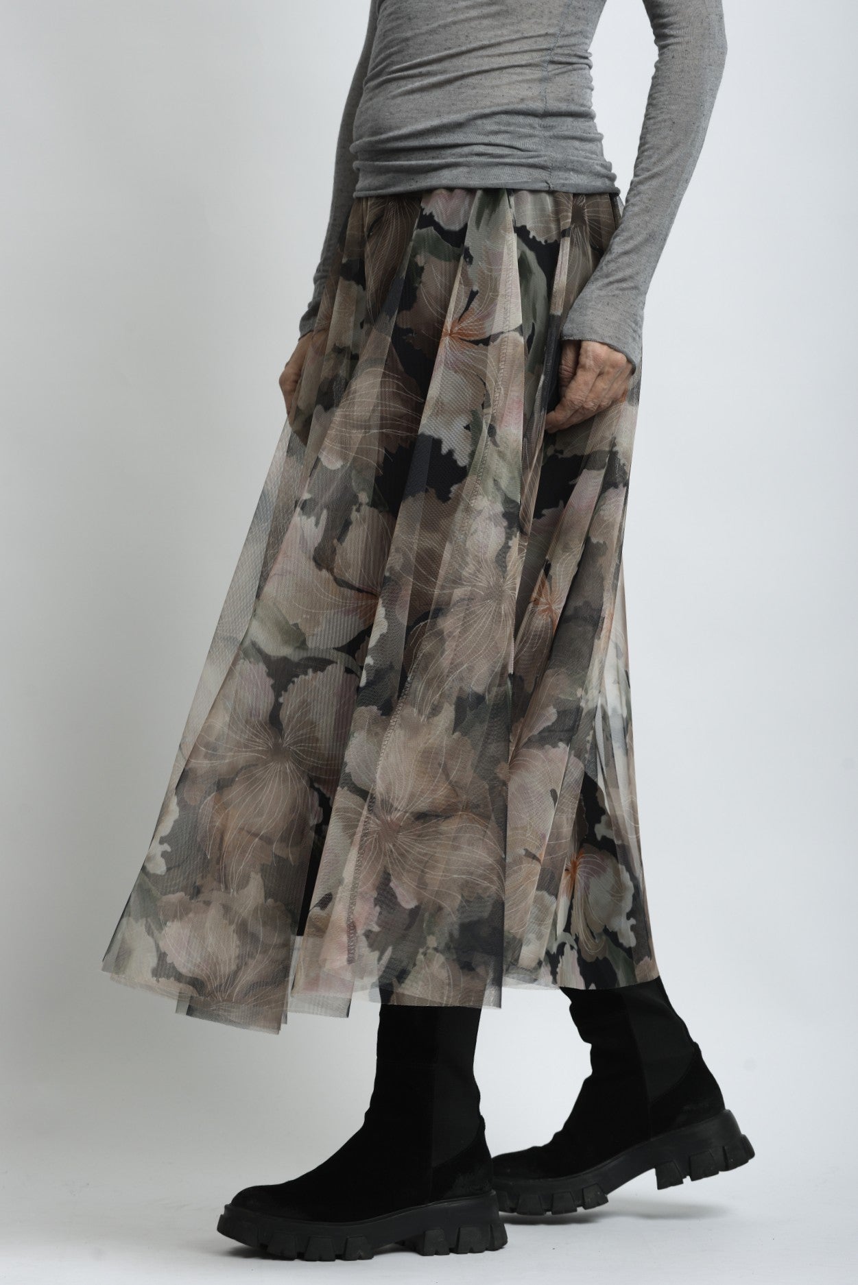 Fustă midi cu imprimeu floral, surprinsă în mișcare, evidențiind transparența stratului exterior.