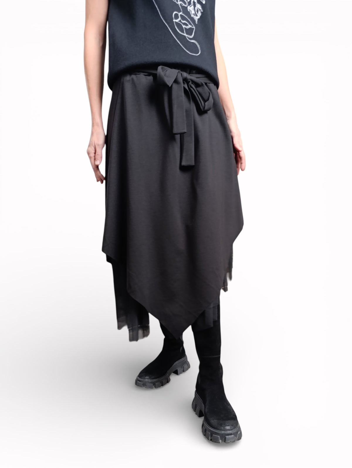 Fustă neagră asimetrică surprinsă în mișcare, evidențiind fluiditatea materialului și stratul de tul.