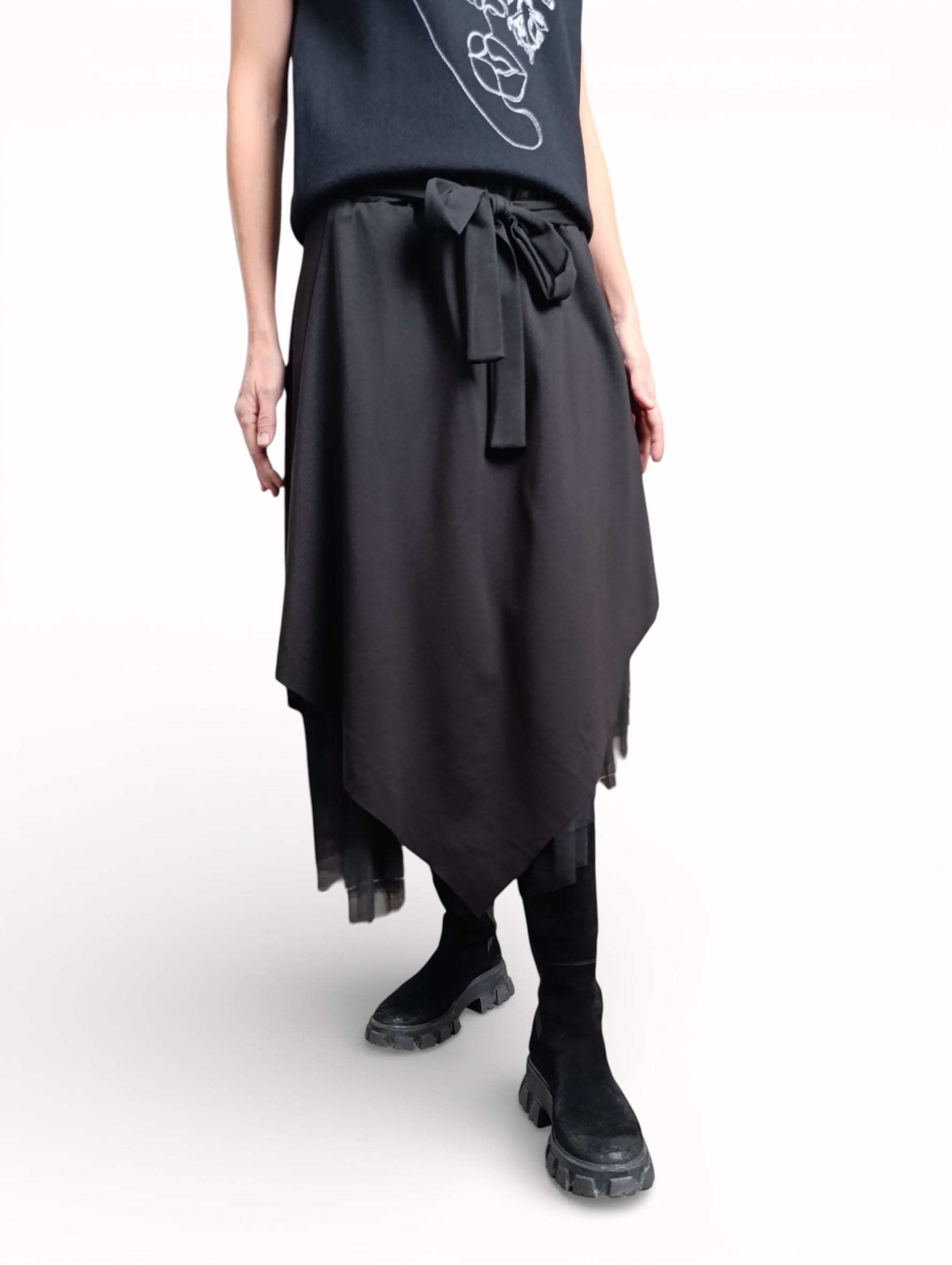 Fustă neagră asimetrică surprinsă în mișcare, evidențiind fluiditatea materialului și stratul de tul.