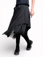 Fustă neagră cu tul, vedere frontală, talie elastică și tiv asimetric, purtată cu bocanci.