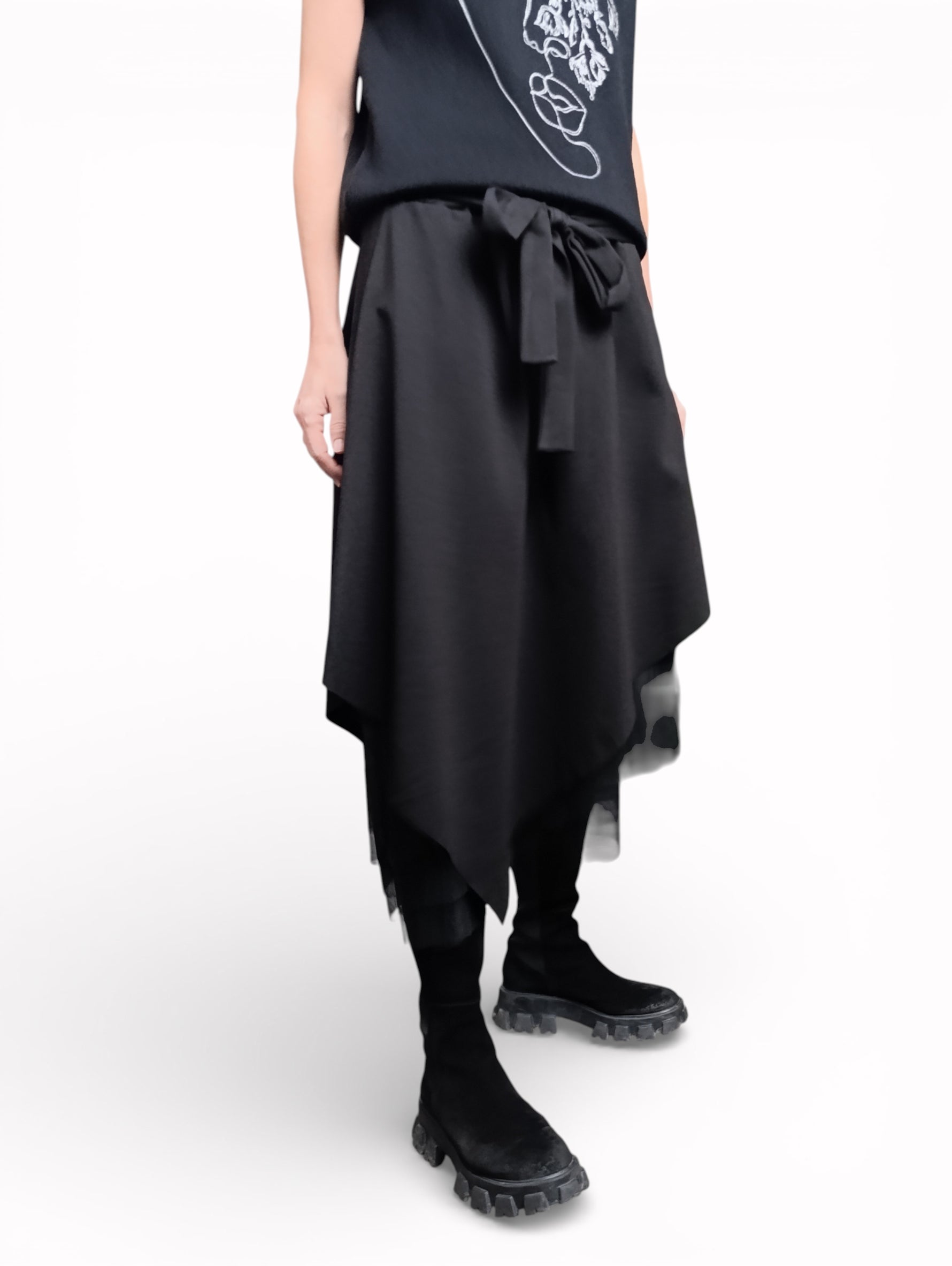 Vedere laterală a fustei negre cu tul, cu suprapuneri și tiv neregulat.