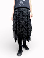 Fustă neagră fluidă cu strat dublu, surprinsă în mișcare, evidențiind transparențele.