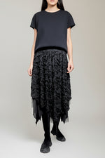 Fustă neagră cu textură devoré și tiv neregulat, purtată cu tricou simplu și bocanci.