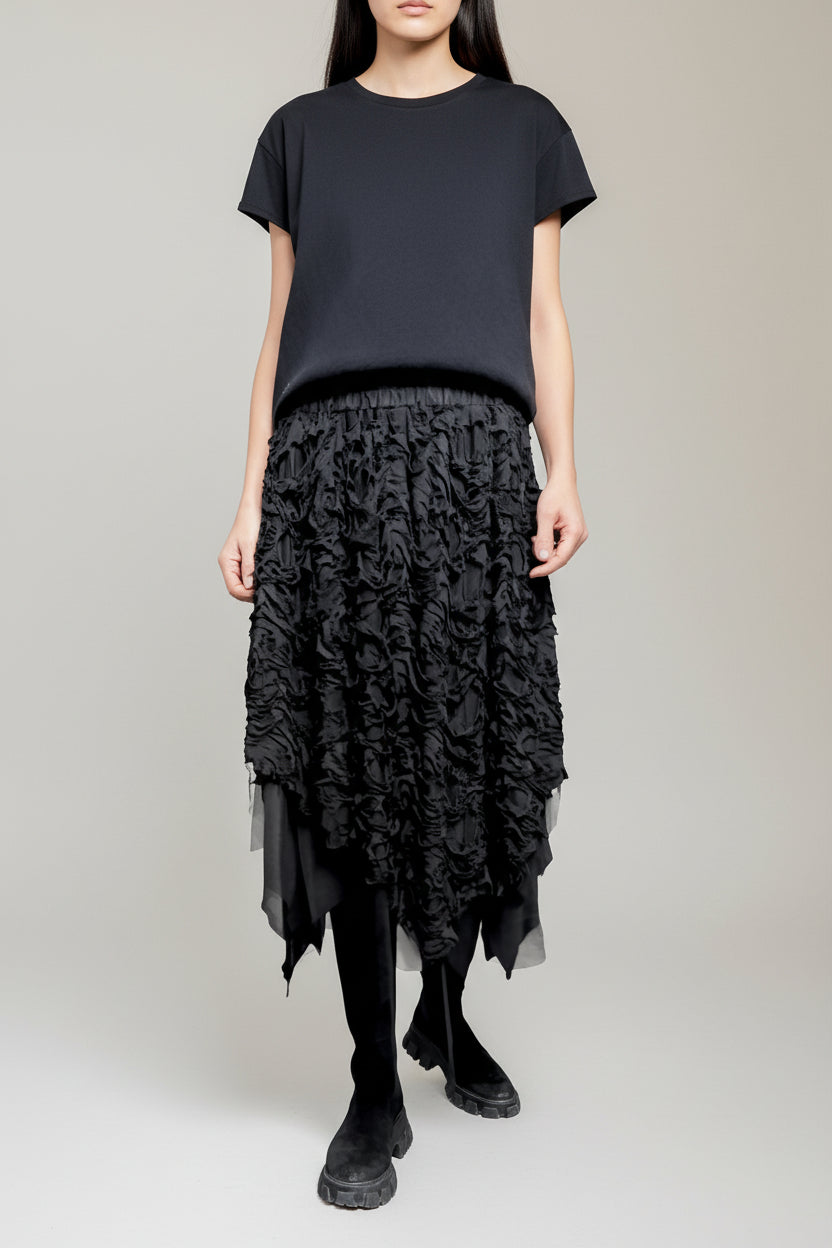 Fustă neagră cu textură devoré și tiv neregulat, purtată cu tricou simplu și bocanci.