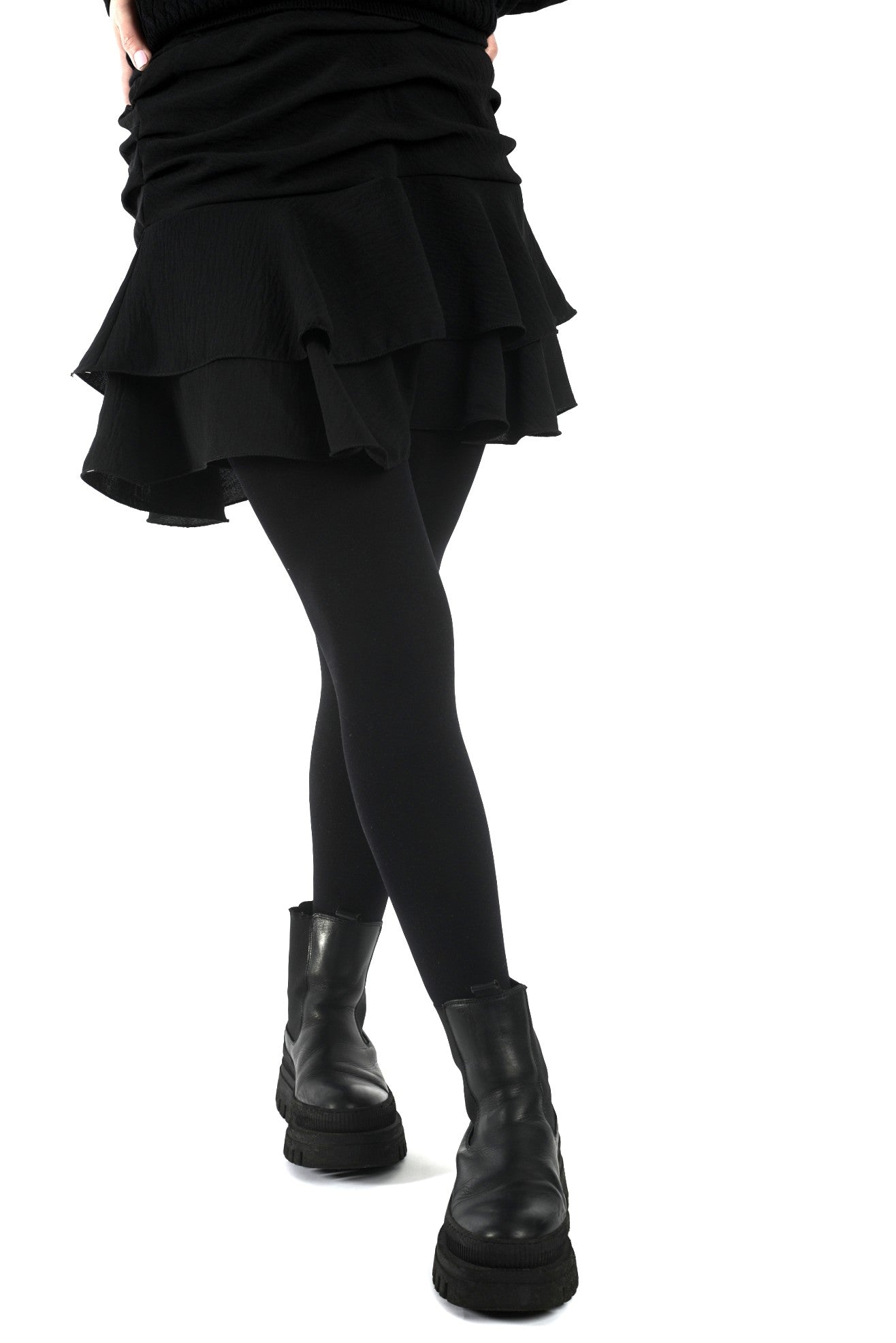 Fustă scurtă neagră cu falduri și jupă pantalon, vedere frontală, purtată cu dresuri și încălțăminte casual.