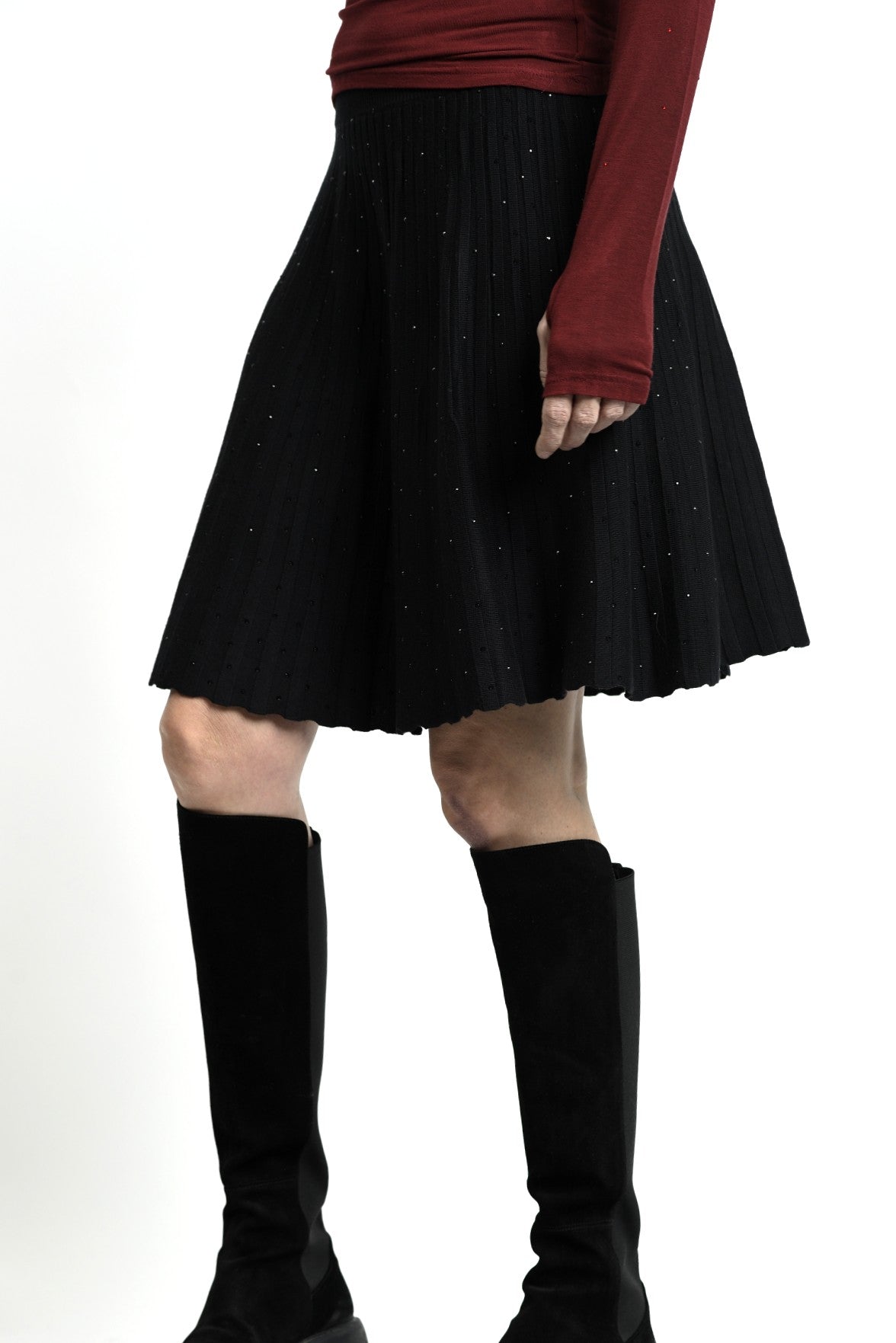 Vedere laterală a fustei scurte din tricot, cu volum discret creat de straturi mici.