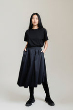 Fustă tip A din bumbac cu buzunare, purtată într-o ținută minimalistă de zi.