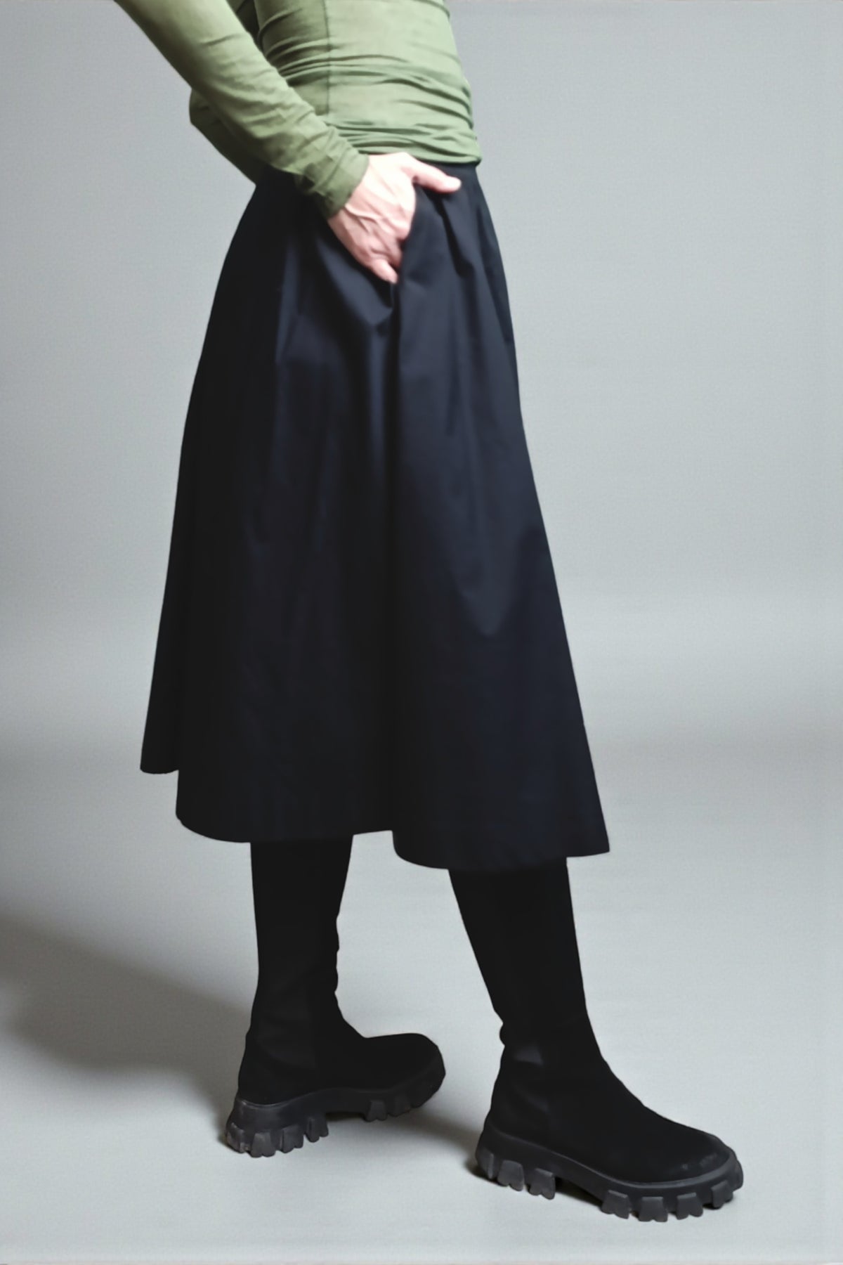 Fustă tip A din bumbac negru, purtată cu top simplu și bocanci, vedere laterală.