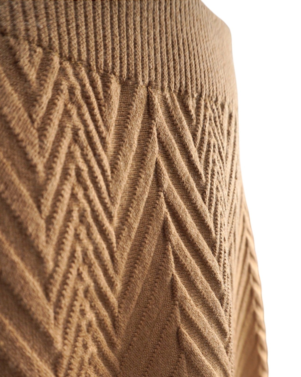 Prim-plan al taliei unei fuste din tricot gros cu model reliefat, culoare camel.