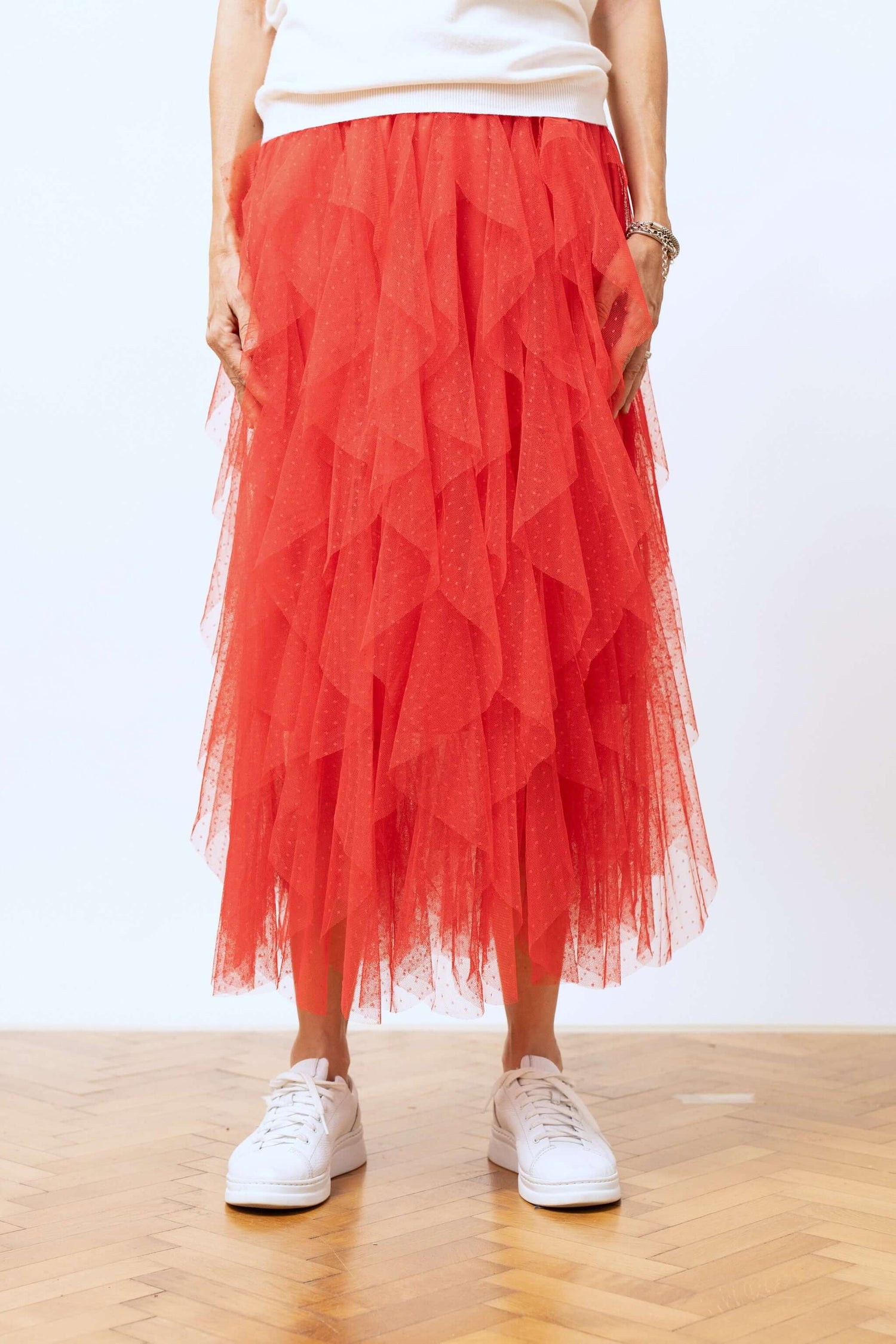 Detaliu frontal al fustei din tulle roșu cu volane suprapuse, textură fină și look romantic.