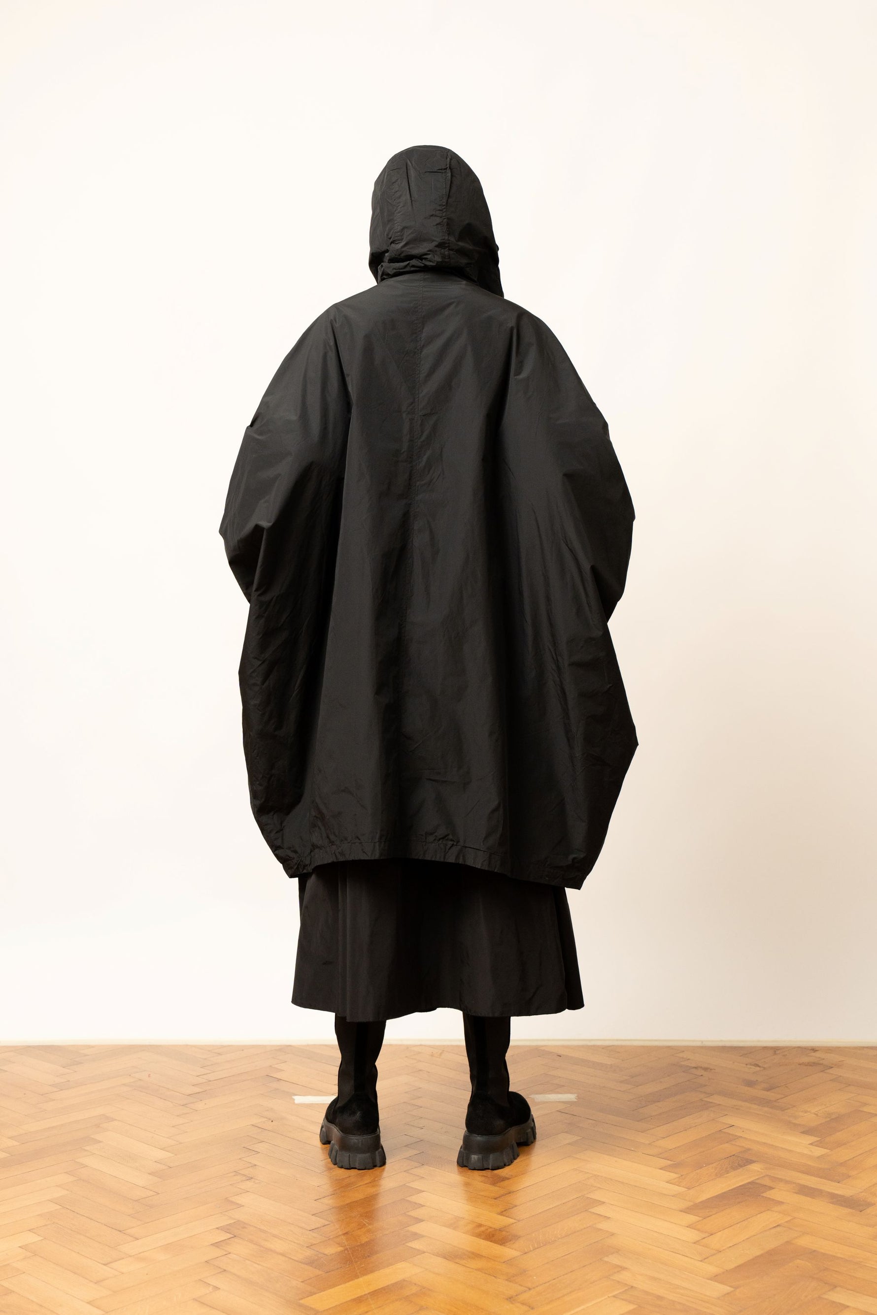 Geacă oversize neagră cu glugă și croială largă, vedere din spate.