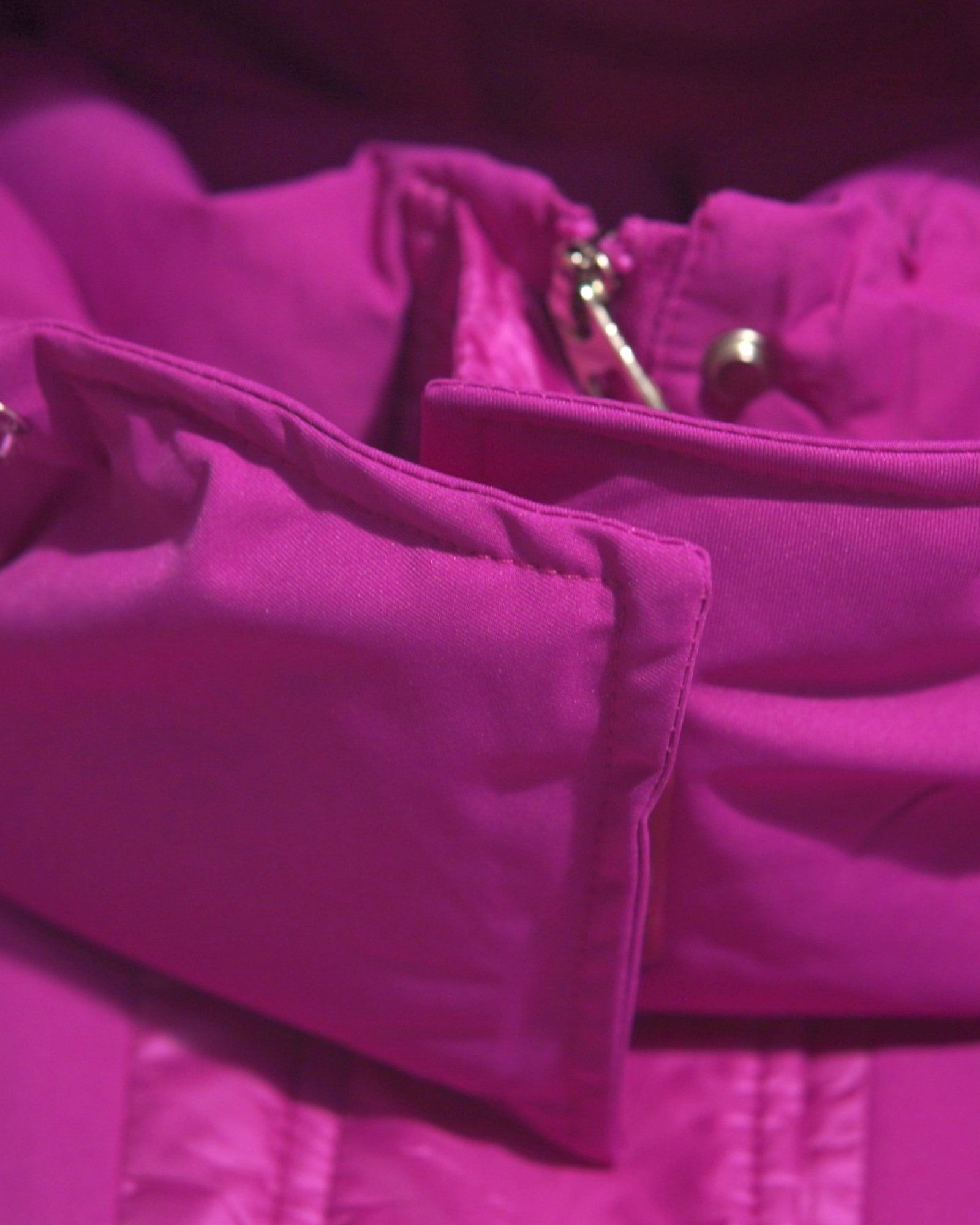 Detaliu al gulerului înalt al gecii fucsia, prevăzut cu fermoar și protecție împotriva frigului.