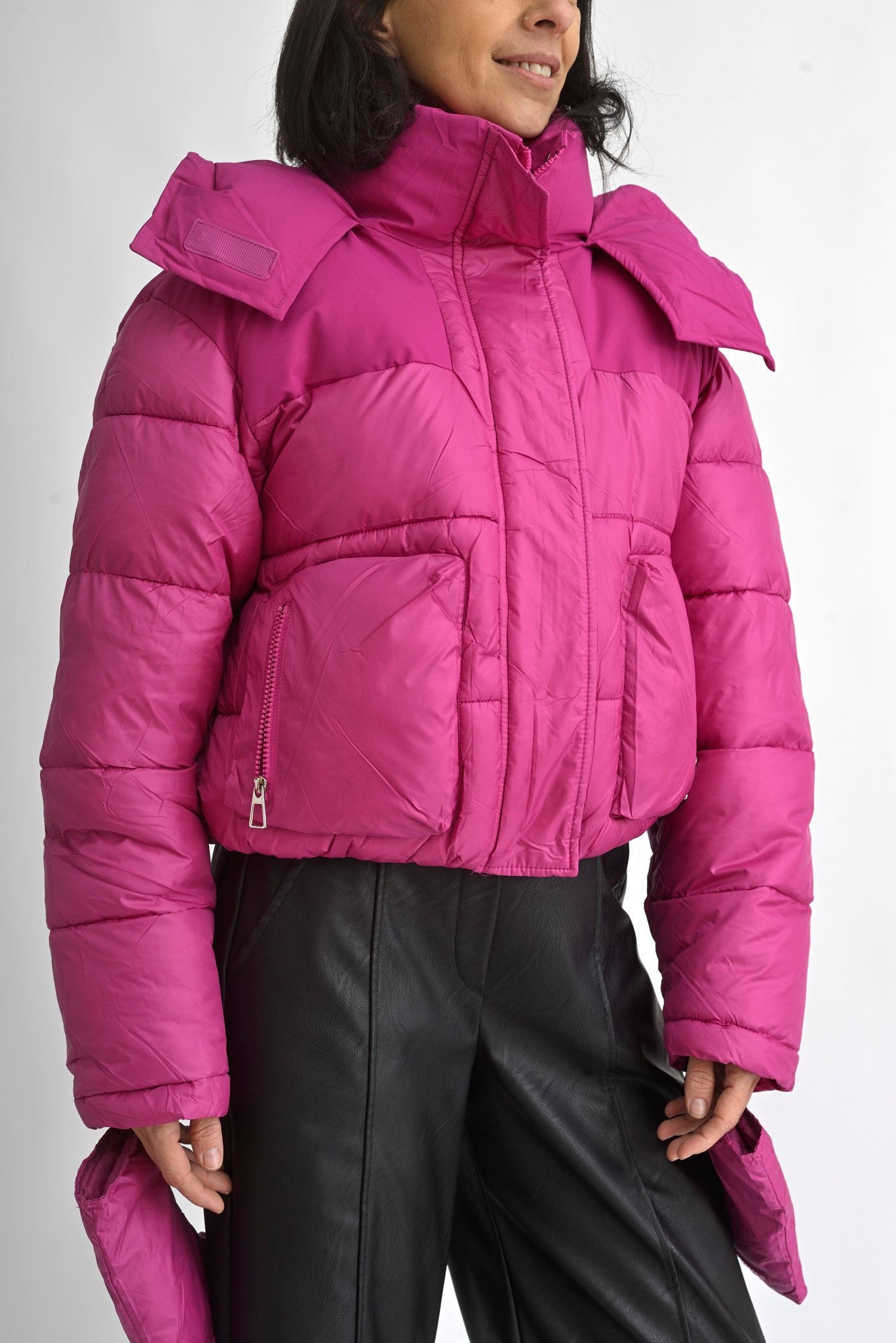 Detaliu al glugii geacă scurtă fucsia, cu guler înalt și sistem de prindere cu fermoar și capse.