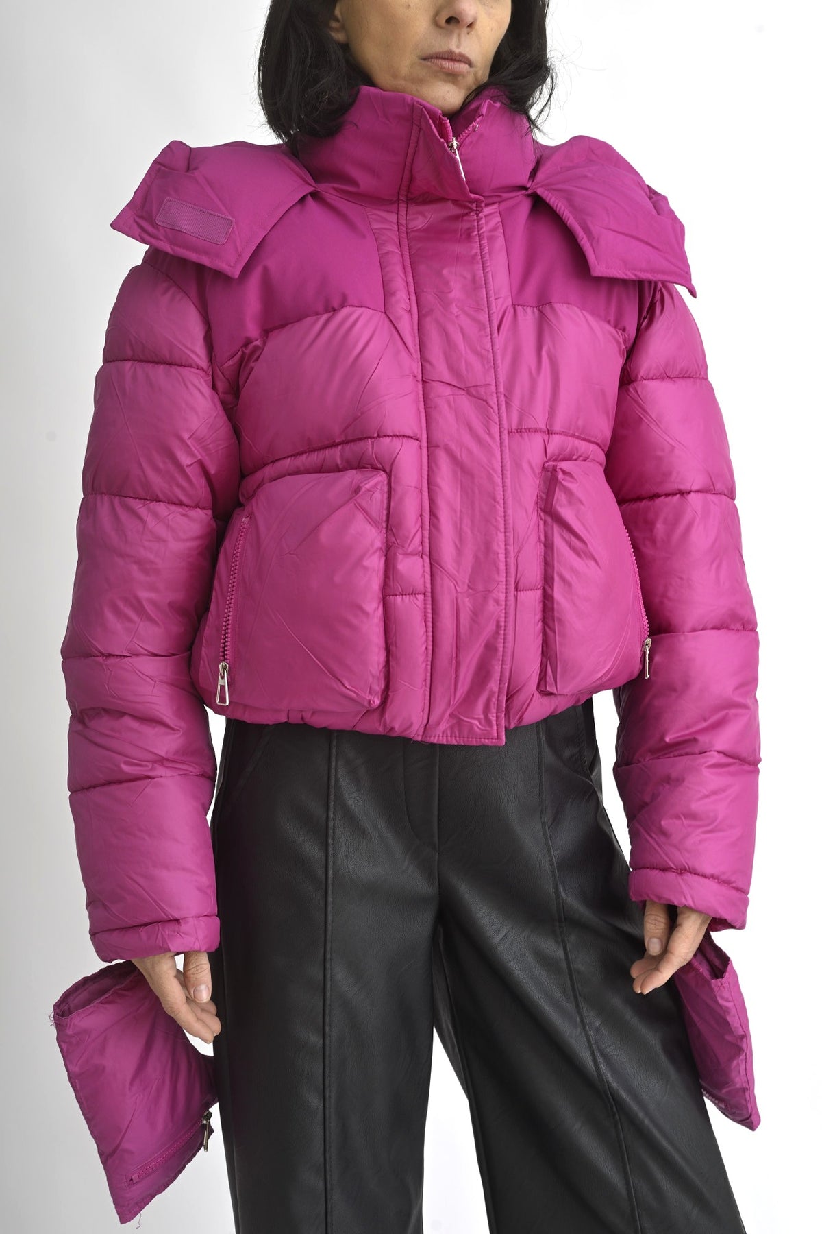 Detaliu al glugii geacă scurtă fucsia, cu guler înalt și sistem de prindere cu fermoar și capse.