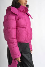 Detaliu al glugii geacă scurtă fucsia, cu guler înalt și sistem de prindere cu fermoar și capse.