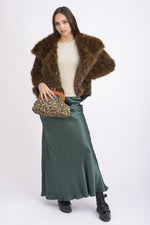 Ținută elegantă completată de o geantă plic cu imprimeu animal print și ramă de lemn, purtată pe umăr.