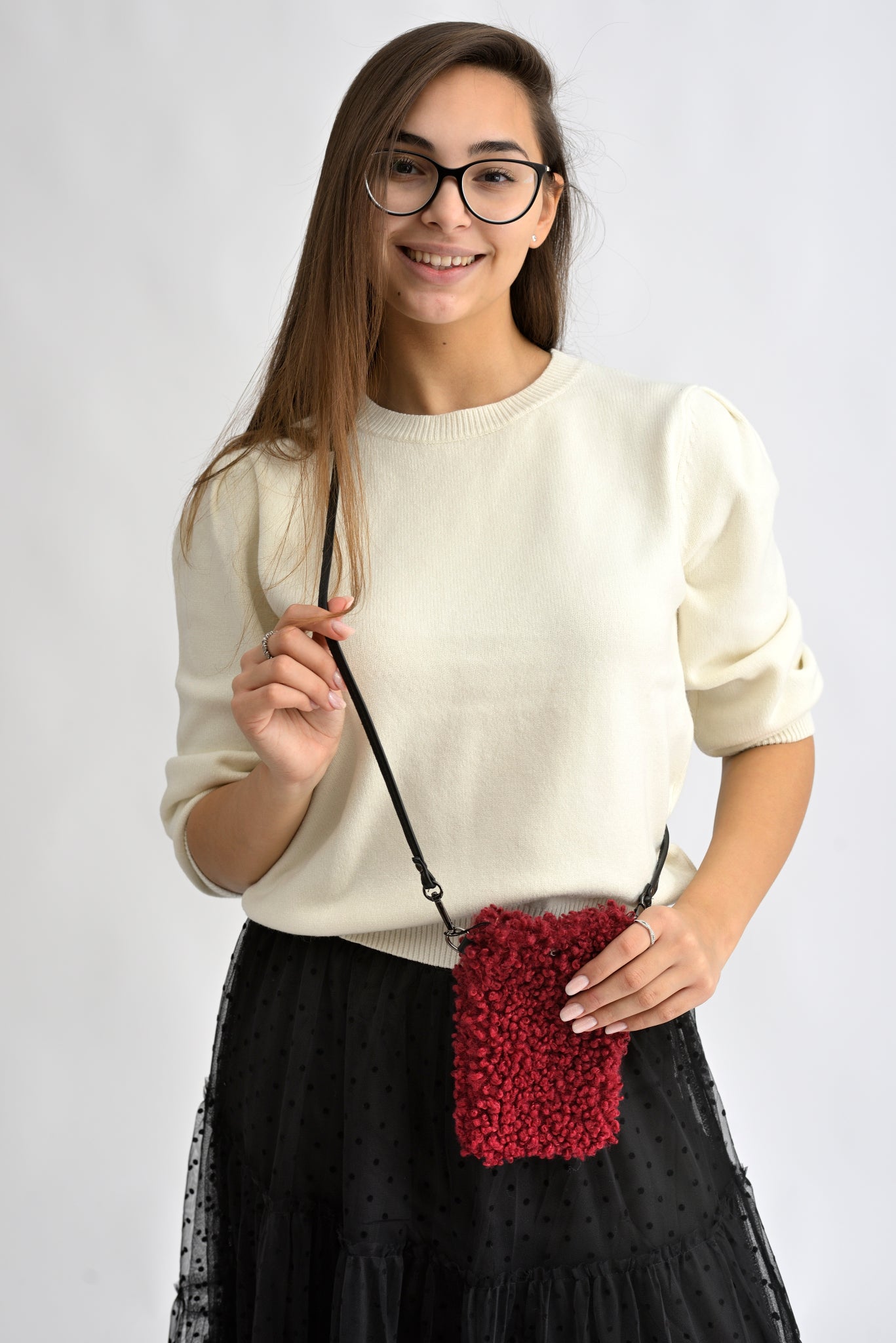 Femeie purtând o geantă mică crossbody pentru telefon, din material bouclé roșu.