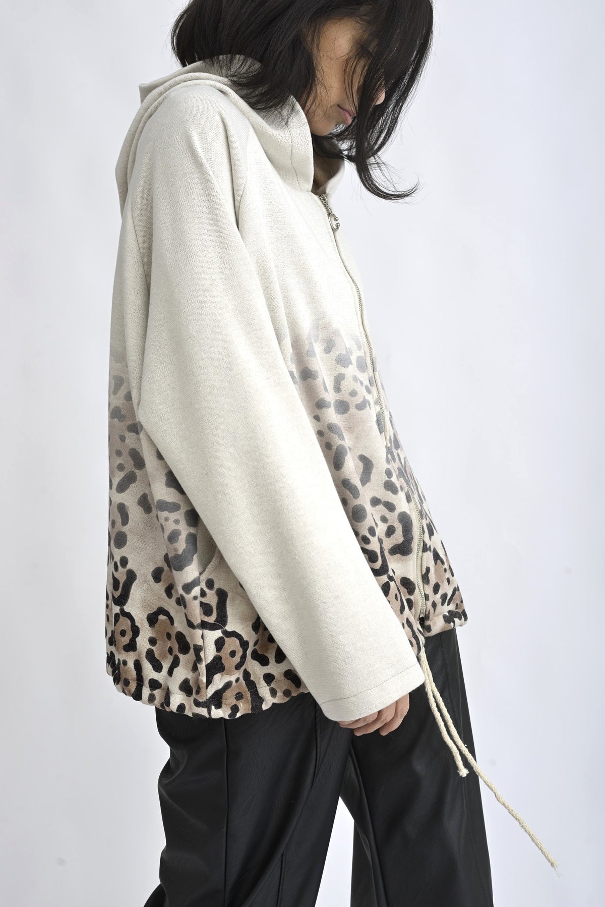 Vedere laterală hanorac bej cu fermoar și glugă, cu mâneci lungi și finisaj lejer.