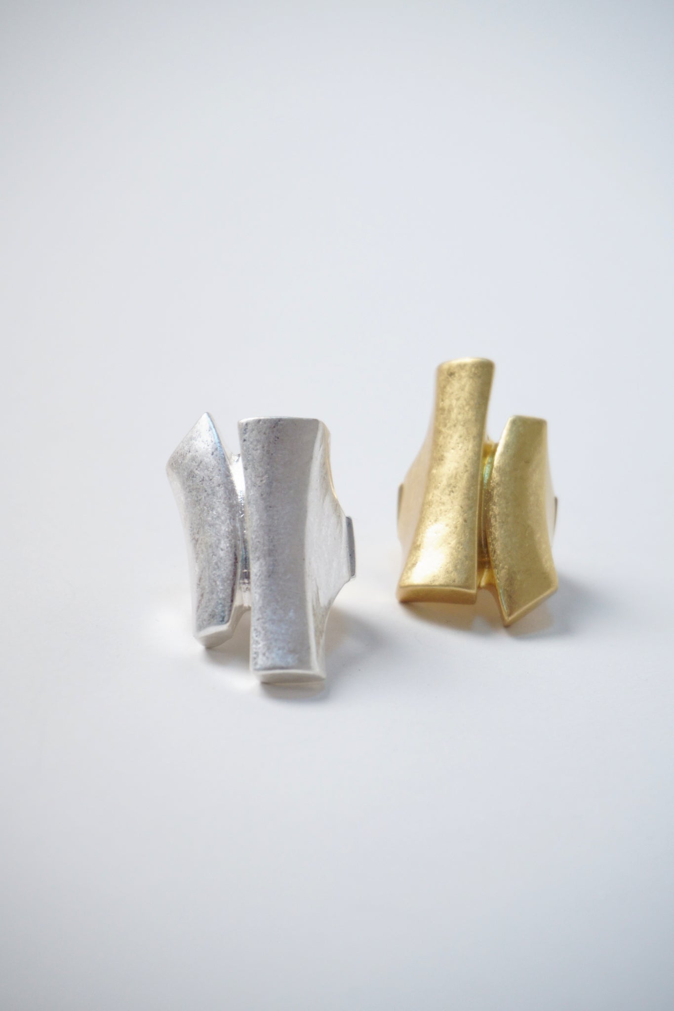 Inel masiv ajustabil, din metal argintiu și auriu, cu forme arhitecturale, unghiuri drepte și volum sculptural.