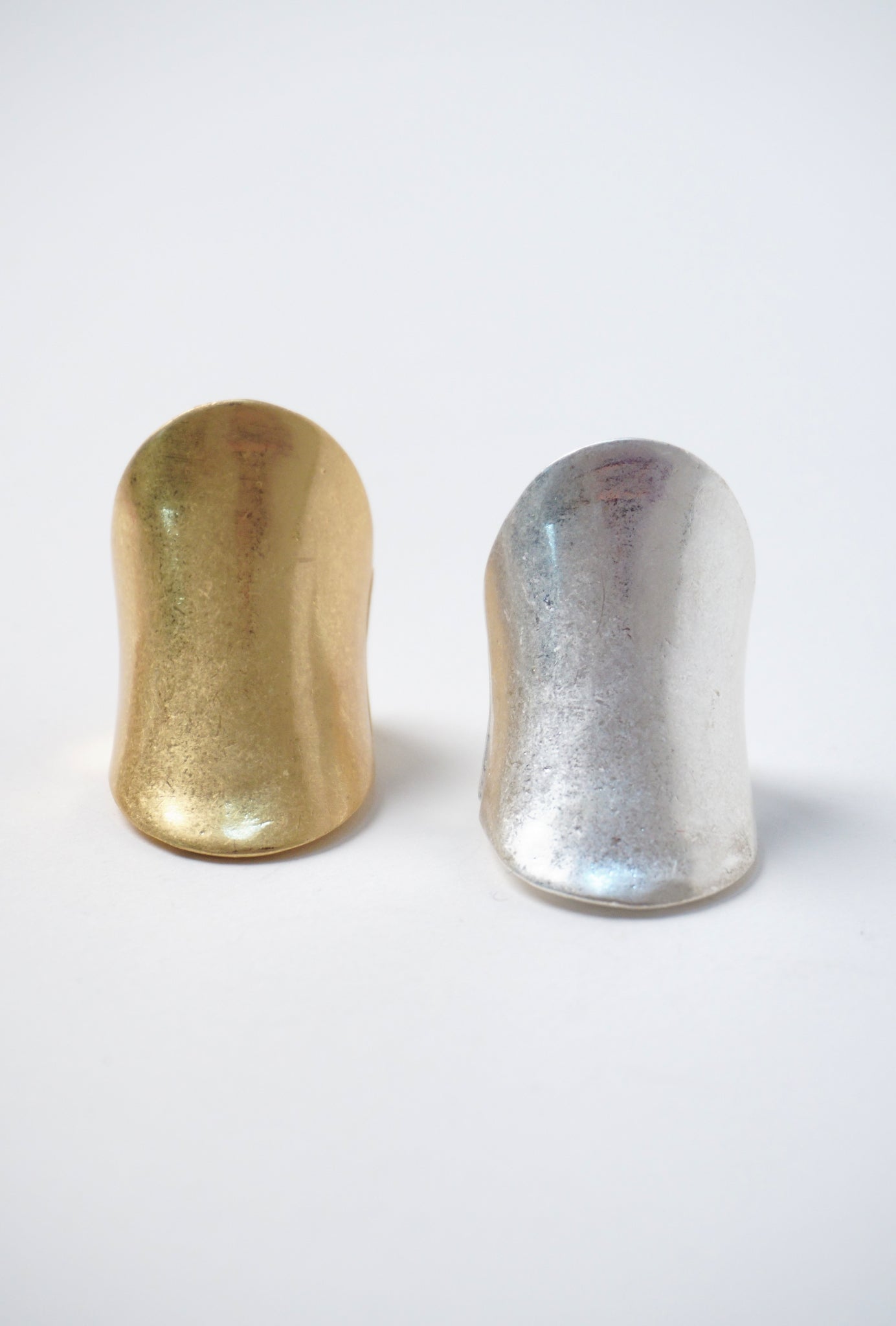 Inel masiv ajustabil, din metal argintiu și auriu, cu design fluid și suprafață curbată.