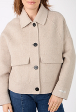 Detaliu jachetă din lână și cașmir: guler clasic, nasturi negri și buzunare aplicate.