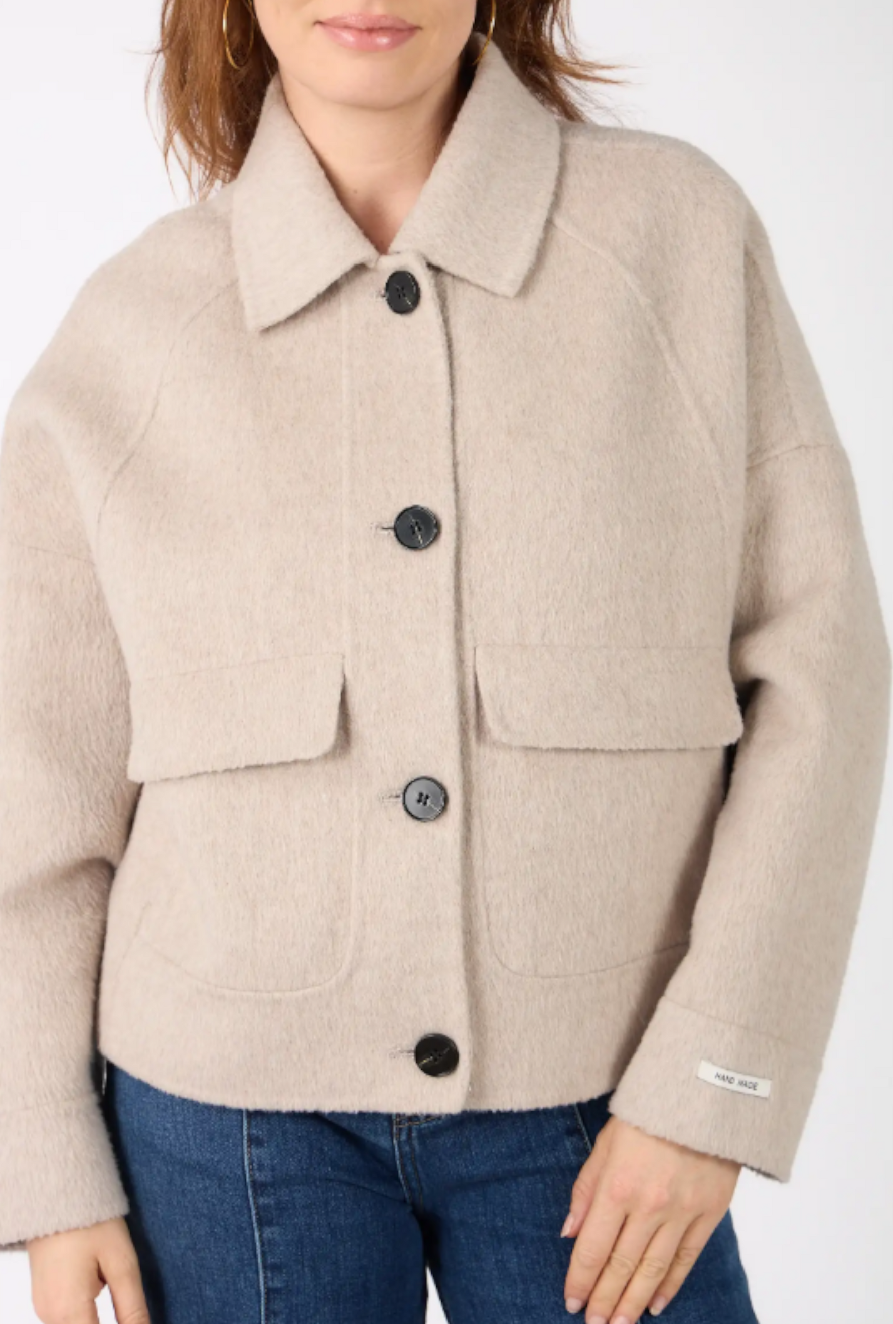 Detaliu jachetă din lână și cașmir: guler clasic, nasturi negri și buzunare aplicate.