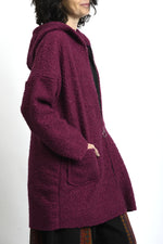 Spatele jachetei midi cu glugă, din material bouclé, cu cădere dreaptă.