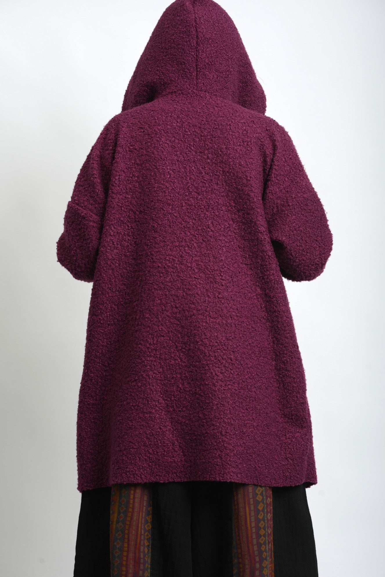 Spatele jachetei midi cu glugă, din material bouclé, cu cădere dreaptă.