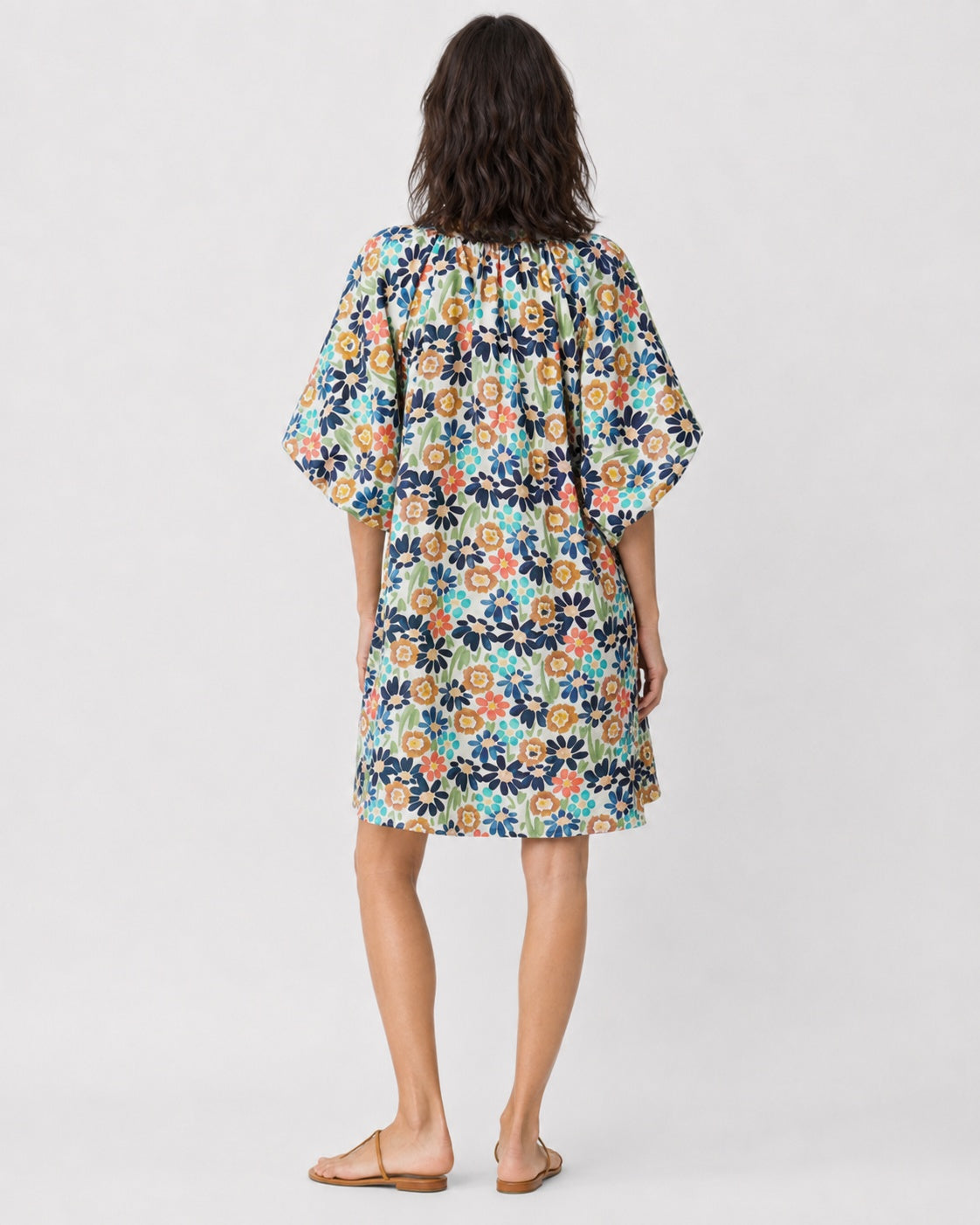Rochie scurtă evazată cu mânecă bufantă și imprimeu cu floricele colorate, în nuanța bleumarin, vedere din spate.