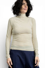 Maletă subțire crem, cu guler înalt și decupaj pentru deget, purtată ca strat de bază.