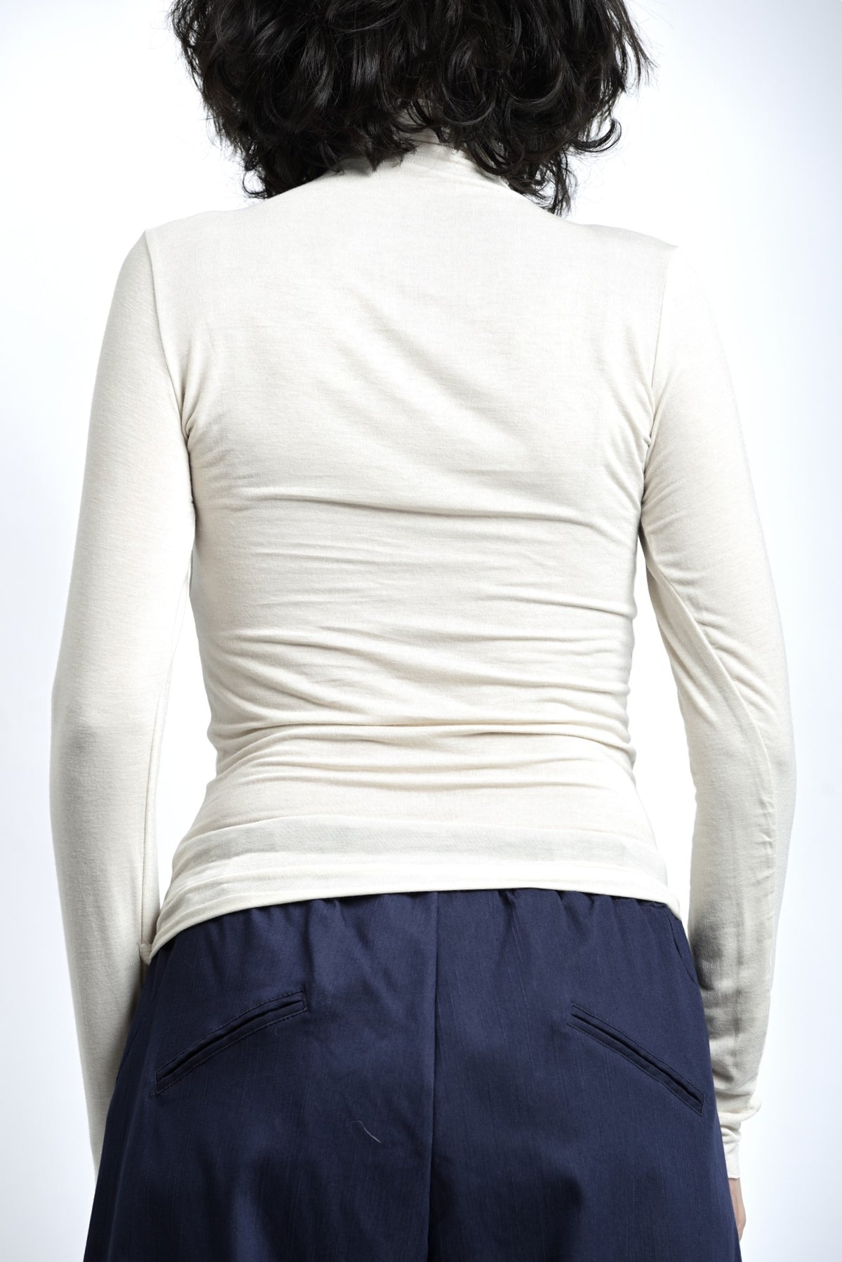 Spatele maletei subțiri fără tiv, cu croială mulată și linie curată.