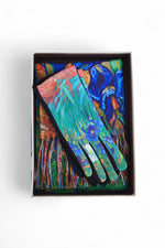 Mănuși cu imprimeu artistic albastru-verde, expuse într-o ramă neagră pentru prezentare.