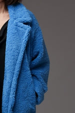 Detaliu palton albastru boucle, cu textură pufosă și rever lat