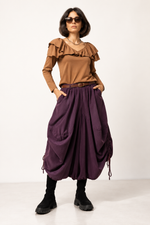 Pantaloni șalvari violet din catifea reiata, cu croială largă, șnur lateral reglabil și buzunare, prezentați din față pe model. All Above Boutique.
