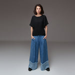 Pantaloni largi din denim cu talie elastică și plii în partea superioară, în nuanță de albastru mediu.