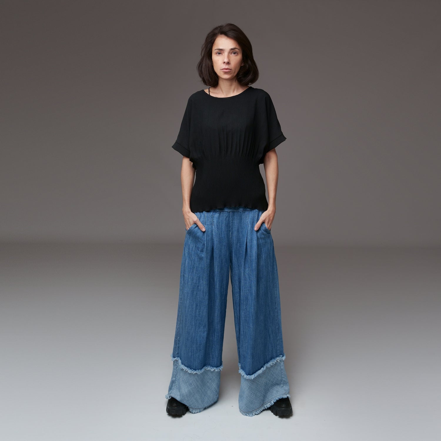 Pantaloni largi din denim cu talie elastică și plii în partea superioară, în nuanță de albastru mediu.