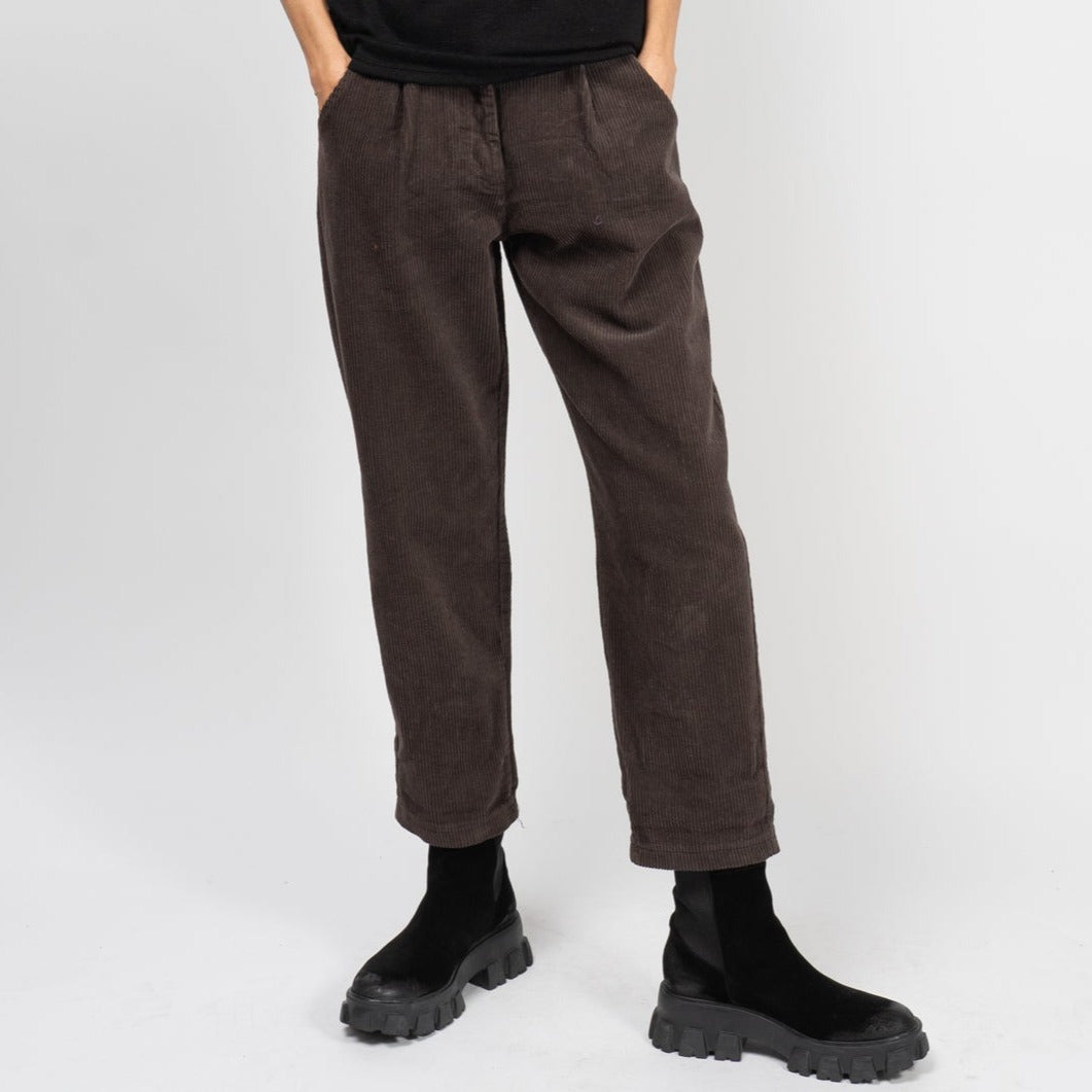Pantaloni bufanți din reiat, vedere din față, croială lejeră cu pense și buzunare oblice.