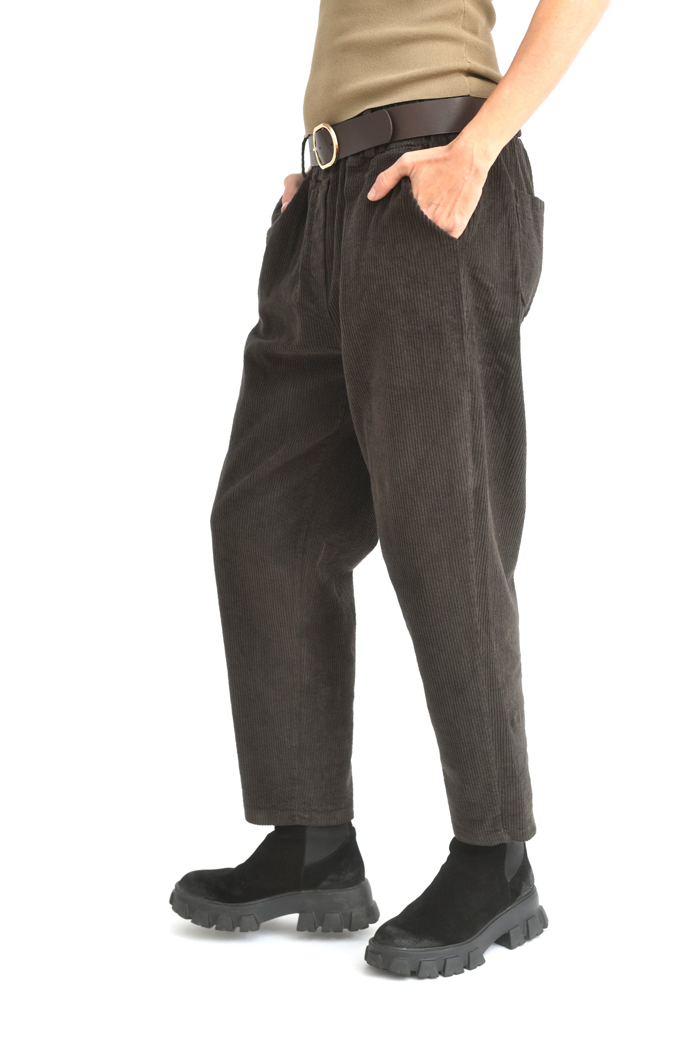 Pantaloni conici maro din catifea reiată, fotografiați din lateral pe model, cu manșete elastice.