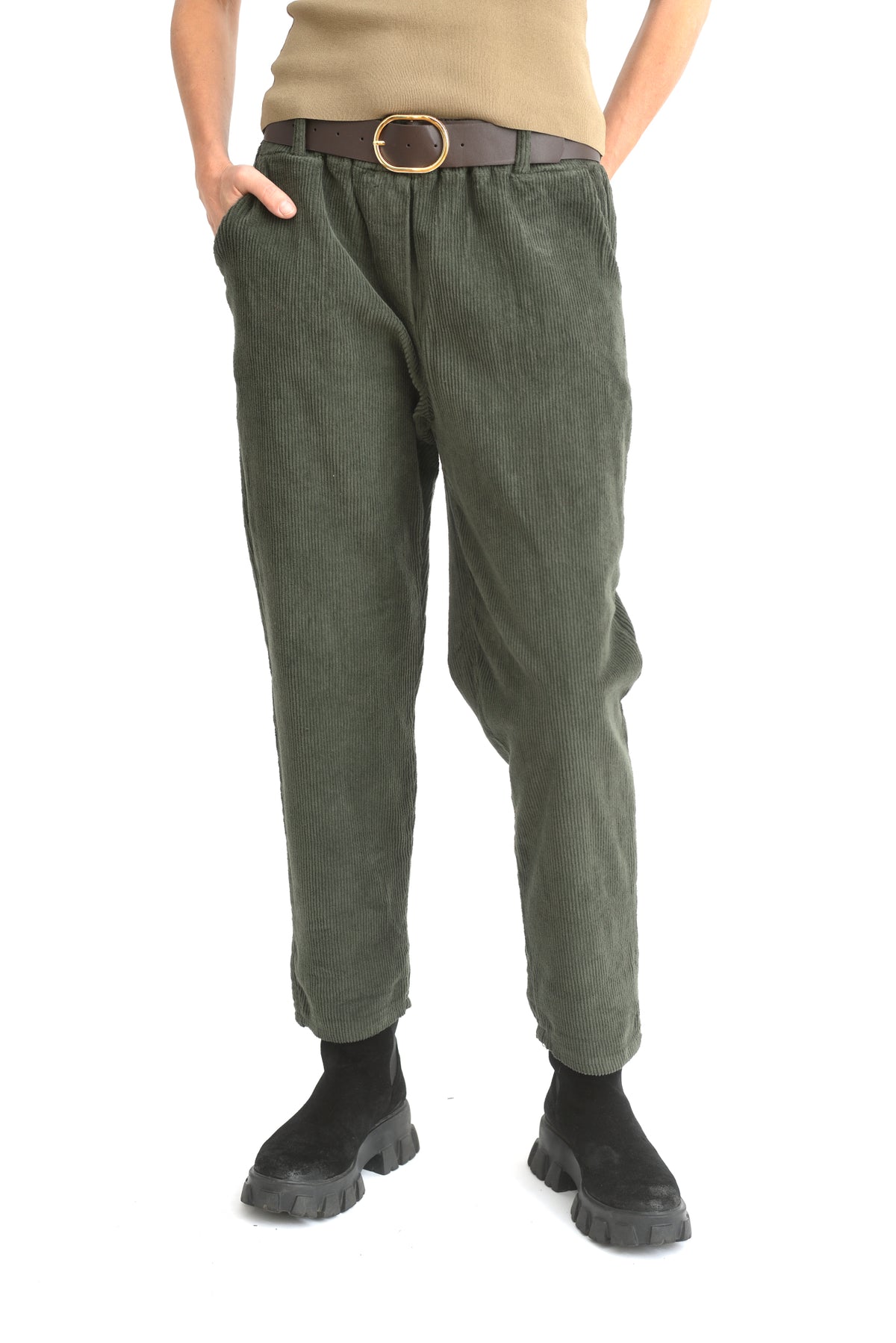 Pantaloni conici din catifea reiată oliv, ilustrați din lateral, evidențiind textura materialului și croiala conică.