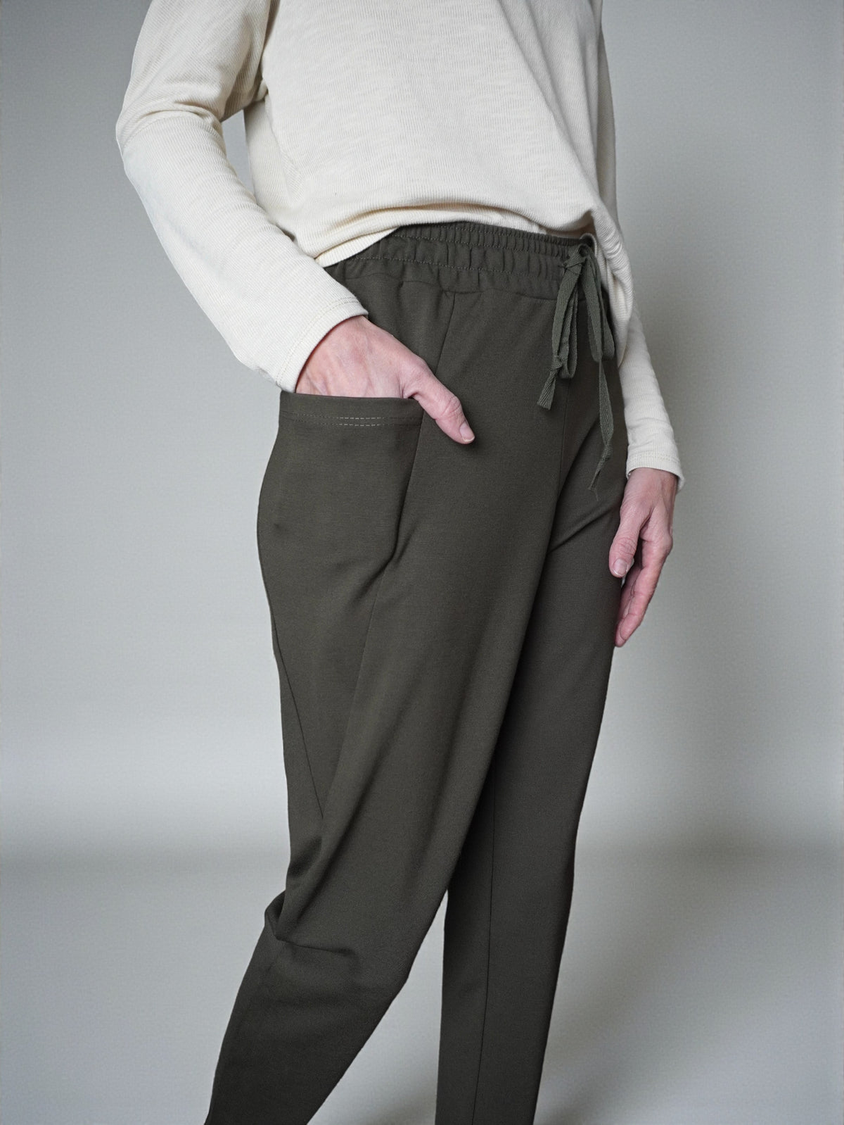 Detaliu talie cu șnur ascuns la pantaloni conici din jerse.