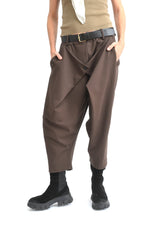 Imagine cu pantaloni conici din jerse maro, croială lejeră, model cu pliuri în față.