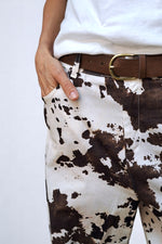 Gros plan pe buzunarul lateral și imprimeul abstract cow print al pantalonilor din bumbac