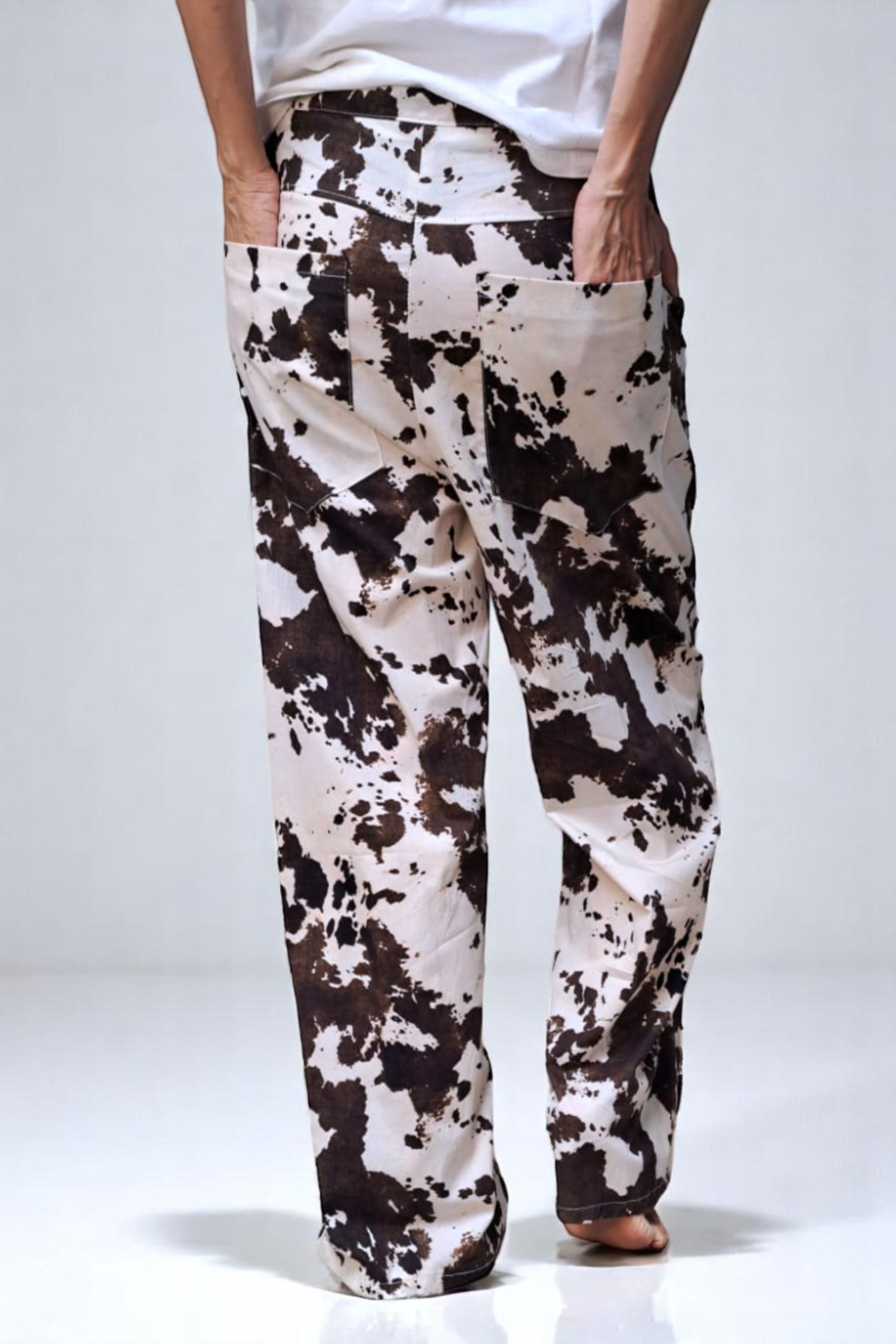  Pantaloni largi cu imprimeu cow print în nuanțe maro și crem, văzuți din spate, cu buzunare aplicate