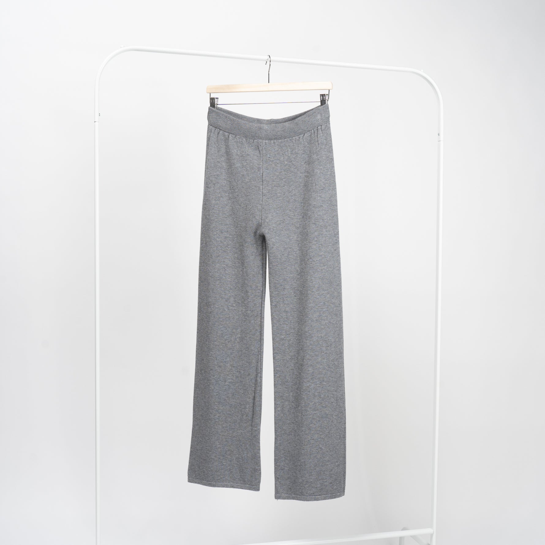 Pantaloni drepți gri din tricot moale, talie elastică înaltă, pe umeraș, vedere frontală.